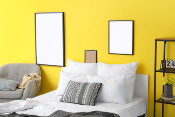 Blank frames hanging on yellow wall in bedroom