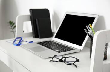 Doctor's workplace with laptop and eyeglasses in medical office