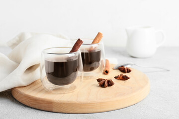 Glasses of tasty coffee with cinnamon on light background
