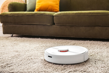 Modern robot vacuum cleaner on soft carpet in room