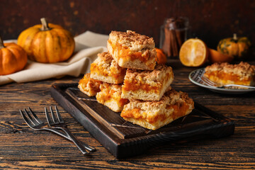 Wooden board with pieces of tasty pumpkin pie on table