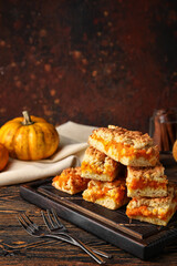 Wooden board with pieces of tasty pumpkin pie on table