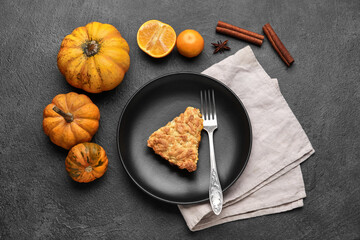 Plate with piece of tasty pumpkin pie and fresh vegetables on black background