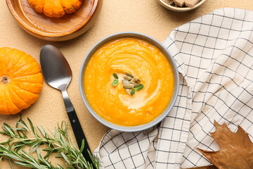 Bowl of tasty pumpkin cream soup on beige background