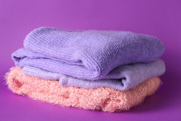 Stack of soft modern sweaters on purple background