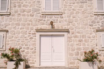 Fototapeta na wymiar House with a stone facade, shutters on the windows and a white door. Perast, Montenegro