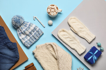 Set of children's clothes with Christmas gift and cup of hot chocolate on color background