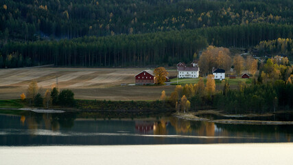 Autumn landscape with farmhouses at the coast of lake Kroderen, in Norway