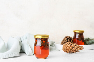 Jar of tasty pine cone jam on light background