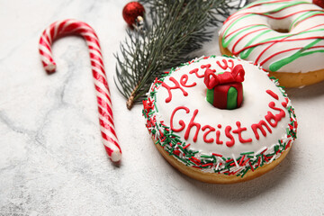 Tasty Christmas donuts with fir tree branch and candy cane on light background, closeup