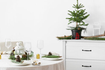 Beautiful table setting with pine cones and fir branches indoors