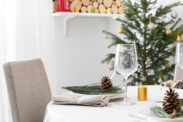 Beautiful table setting with pine cones and fir branches indoors