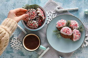 Woman drinking cup of coffee with tasty candy cane cookies on blue background