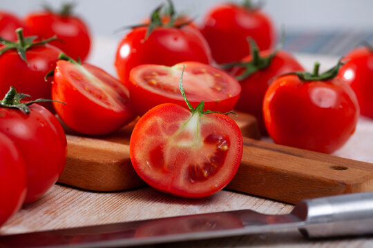 Image of cut fresh tomatoes on wooden table in home kitchen
