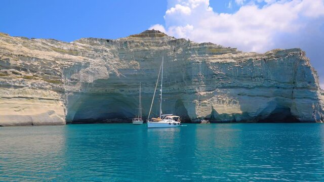 Boats anchored by the iconic rocky cliffs of Kleftiko Beach on a sunny summer day on Milos Island, Greece