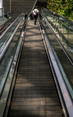 Naklejka premium Bangkok, Thailand - Apr 16, 2021 : Modern escalator staircase with people for facilities in a contemporary building. No focus, specifically.