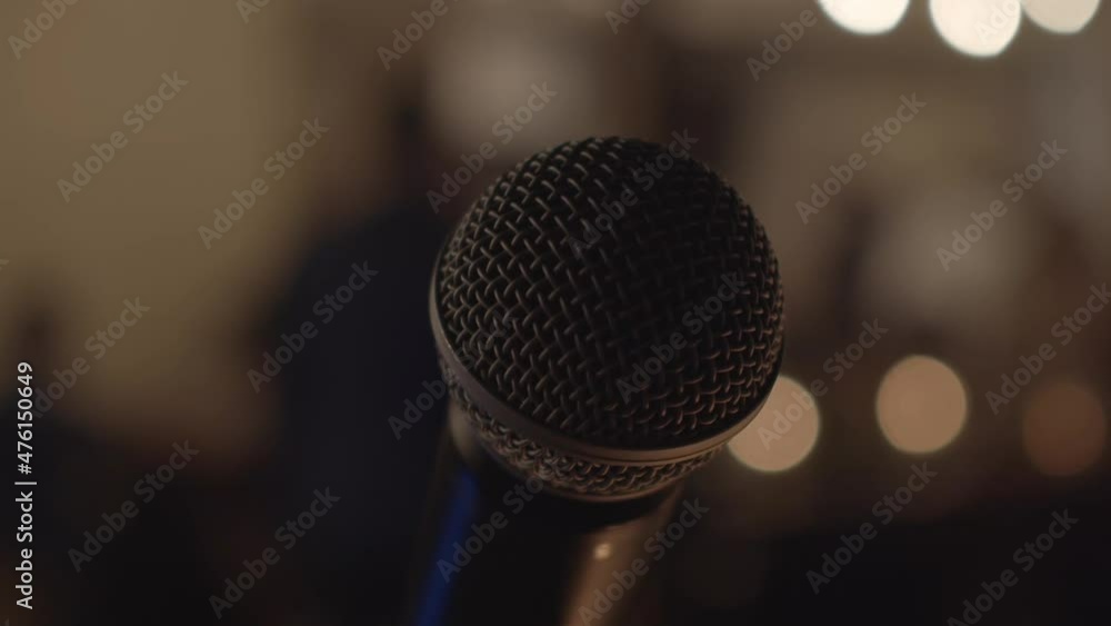 Poster circular view of a professional microphone on an evening stage in a building with blurred background