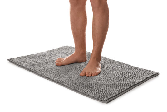 Man standing on soft grey bath mat against white background, closeup - Powered by Adobe