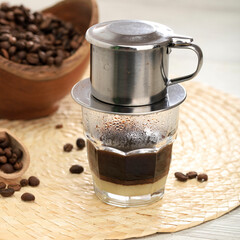 Vietnamese black coffee brewed in French drip filter on turquoise wooden table