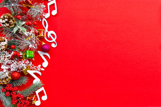 Composition with notes and christmas decorations on red background.