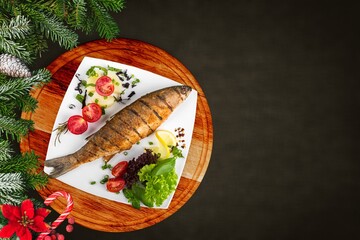 Tasty fish for preparation for the holiday Christmas with Christmas trees and Christmas decorations.
