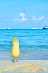 piña colada on the sand on the beaches of Cancun, Mexico. sea background out of focus with yachts. copy space for advertising. close up view.