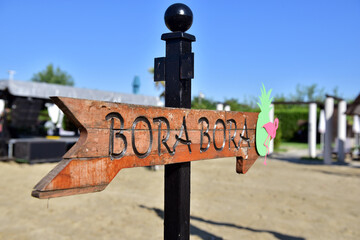 Closeup shot of a wooden sign pointing to bora bora