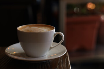 Cup of aromatic coffee with foam on table in cafe. Space for text