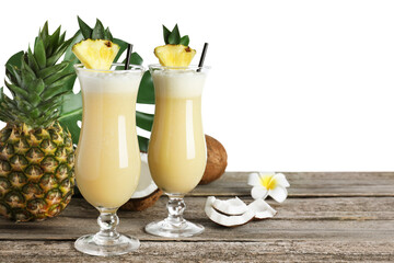 Tasty Pina Colada cocktail and ingredients on wooden table against white background, space for text