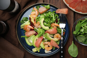 Delicious pomelo salad with shrimps served on wooden table, flat lay