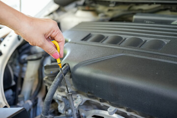 Vehicle safety concept, Woman's hand checking car engine before driving. Car Maintenance engine oil level checking.