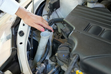 Vehicle safety concept, Woman's hand checking car engine before driving. Car Maintenance glass cleaner water checking.