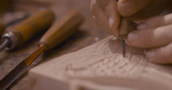 A wood carving craftsman working on small details on an art piece