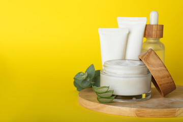 Body cream and other cosmetics, aloe with eucalyptus on yellow background. Space for text