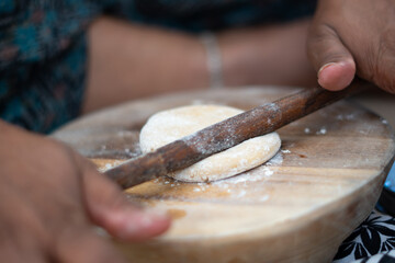 Closeup shot of hands of an Indian female making roti using the Belan roller 