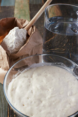 Wheat flour starter culture is ready to be added to the dough. Spoon with flour and water on the table. Front view.