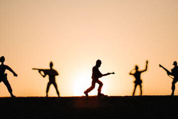 Silhouette of toy soldiers in front of the sun during the sunset. Soldiers background. War background. Soldiers in war concept