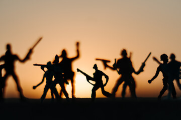 Fototapeta na wymiar Silhouette of toy soldiers in front of the sun during the sunset. Soldiers background. War background. Soldiers in war concept