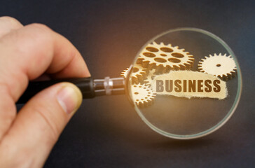 In his hand is a magnifying glass through which you can see the gears and scrap of paper with the inscription - BUSINESS