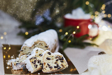Obraz na płótnie Canvas Festive Christmas stollen, Christstollen - classic Christmas yeast bread. Hot beverage with marshmallow. Cozy aesthetic dinner. Christmas tradition with bokeh background. Festive background