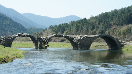 The old arched stone bridge made many years ago in the countryside of the China 