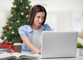 Happy pretty young woman freelancer working remote at a laptop at home before Christmas