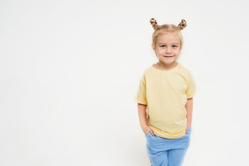 A girl on a light background in a yellow T-shirt and blue pants. Happy child on a bright background. A place for text about advertising about children. Sports and comfortable clothes for children.