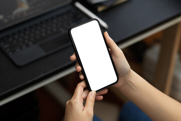 A female relaxed on her smartphone at her desk.
