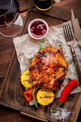 Baked chicken with crispy crust and barbecue sauce on a wooden board. Homemade fried chicken served with vegetables, top view