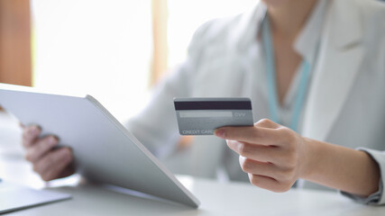 Business woman holding a digital tablet and a credit card