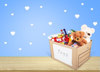 Donation concept. Donate box with clothes, books, and toys on the desk