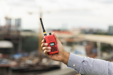 Engineer man or architect use radio communication with white safety helmet in city construction site . Standing on rooftop building construction at capital.