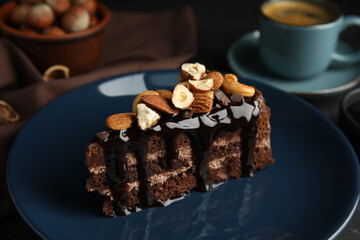 Piece of tasty homemade chocolate cake with nuts on plate, closeup