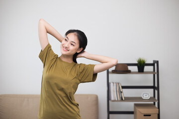 Attractive asian young fitness woman stretching arms warming up before workout at home. Beautiful smiling Female wearing sportswear exercise training yoga in living room.